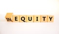 Inequity or equity symbol. Turned wooden cubes and changed the concept word Inequity to Equity. Beautiful white table white