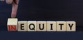 Inequity or equity symbol. Turned wooden cubes and changed the concept word Inequity to Equity. Beautiful grey table grey