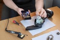 Inexperienced repairman looks at smartphone to correctly connect wires to electric motor during repair