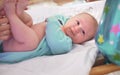 Infant baby boy laying on changing table, as his mother is preparing him, holding feet Royalty Free Stock Photo