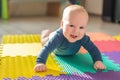Infant baby boy playing on colorful soft mat. Little child making first crawling steps on floor. Top view from above Royalty Free Stock Photo