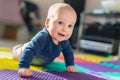 Infant baby boy playing on colorful soft mat. Little child making first crawling steps on floor. Top view from above