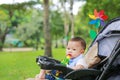 Infant baby boy playing toy in hand sitting on stroller in nature park Royalty Free Stock Photo