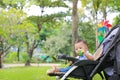 Infant baby boy playing toy in hand sitting on stroller in nature park Royalty Free Stock Photo
