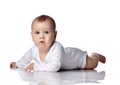 Infant baby boy toddler in diaper and white bodysuit is lying on floor on his stomach, crawling, watching unknown Royalty Free Stock Photo