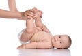 Infant baby girl kid in diaper does exercises, bending knees with her adult coach, mother and looks at camera. Side view Royalty Free Stock Photo