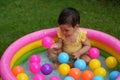 infant baby girl playing water with colorful plastic balls in inflatable pool Royalty Free Stock Photo