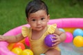 infant baby girl playing water with colorful plastic balls in inflatable pool Royalty Free Stock Photo