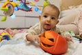 Infant baby girl plays with halloween pumpkin on the floor