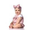 Infant baby girl toddler in polka-dot dress and headband with bow sits on the white floor looks at camera with interest Royalty Free Stock Photo