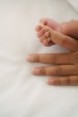 Infant baby hand holding mom finger on white bed