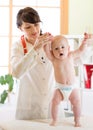 Happy baby at health exam at doctor`s office. Pediatrician supports child while he is standing Royalty Free Stock Photo