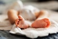 Infant baby laying on white blanket with barefeet, tiny toes in natural light