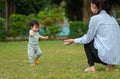 infant baby learn walking first step on grass field with mother helping in park Royalty Free Stock Photo