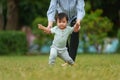 infant baby learn walking first step on grass field with mother holding hand helping in park Royalty Free Stock Photo