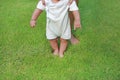 Infant baby learning to walk with his mother on the green grass. First steps Royalty Free Stock Photo