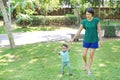 Infant baby learning to walk with his mother on the green grass. First steps Royalty Free Stock Photo