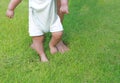 Infant baby learning to walk with his mother on the green grass. First steps Royalty Free Stock Photo