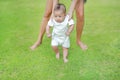 Infant baby learning to walk with his mother on the green grass. First steps Royalty Free Stock Photo