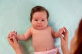 Infant baby lying on back on turquoise blanket holding hands of mother. Mom doing morning exercises for four month old daughter. Royalty Free Stock Photo