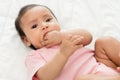 infant baby putting hands in mouth and sucking fingers on bed Royalty Free Stock Photo