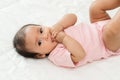 infant baby putting hands in mouth and sucking fingers on bed Royalty Free Stock Photo