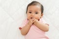 infant baby putting hands in mouth and sucking fingers on bed Royalty Free Stock Photo