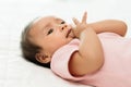 infant baby putting hands in mouth and sucking fingers on bed Royalty Free Stock Photo