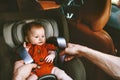 Infant baby in safety car seat and father fastens belt