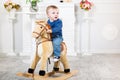 Infant boy in blue sweater and jeans sits on a toy horse. He does not like what is happening. Disgust, loathing Royalty Free Stock Photo
