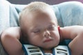 Infant boy sleeps peacefully secured with seat belts