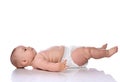 Infant child baby girl kid in diaper is lying on her back sideways to camera, looking up and holding her legs up Royalty Free Stock Photo