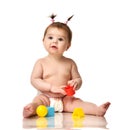 Infant child baby toddler sitting in diaper with yellow blue and red educational toys playing isolated Royalty Free Stock Photo