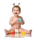 Infant child baby toddler sitting in diaper with yellow blue and red educational toys playing isolated Royalty Free Stock Photo