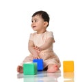 Infant child baby toddler sitting in dress with green blue and yellow brick toy playing isolated on a white Royalty Free Stock Photo