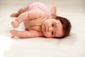 Infant child learning to turn over on blanket. Portrait of baby girl lying on her side trying to roll over. Room for text