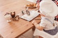 Infant cook baby portrait wearing chef hat playing with dough at kitchen table. Royalty Free Stock Photo