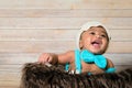 Infant dogla boy wearing hat and bow tie sitting in a fluffy furry basket wooden background modern studio shoot vintage look. Royalty Free Stock Photo