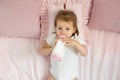 Infant drinks a mixture of milk from a bottle lying on a bed with pillows Royalty Free Stock Photo