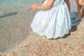 Infant girl in blue dress taking first steps in the sand with mom help at the sunny beach Royalty Free Stock Photo