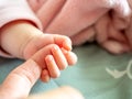 Infant hand grasp parent finger on bed