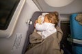 The infant passenger safely and comfortably sleeps in the baby bussinet on a long flight. Royalty Free Stock Photo