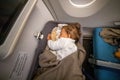 the infant passenger safely and comfortably sleeps in the baby bussinet on a long flight. Royalty Free Stock Photo