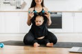 Infant raising dumbbells with mom& x27;s help on yoga mat indoors Royalty Free Stock Photo