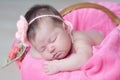 Infant sleeping in basket with knitted flower on head, baby girl lying on pink blanket, cute child, newborn Royalty Free Stock Photo