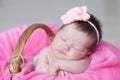 Infant sleeping in basket with knitted flower on head, baby girl lying on pink blanket, cute child, newborn Royalty Free Stock Photo