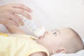 Infants aged 5-6 months are drinking milk from the bottle. By the hands of the mother. Royalty Free Stock Photo