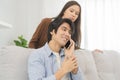 Infidelity, suspicion asian young couple love, husband using mobile phone, wife spying his boyfriend while man chat a message, Royalty Free Stock Photo