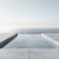 Infinity pool with concrete deck, vast ocean view, bright sky, minimalist design, tranquil luxury. Royalty Free Stock Photo