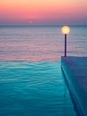 Infinity pool with ocean and sunset view, lamp lit. Royalty Free Stock Photo